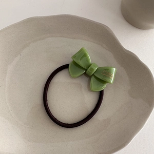Detail of green acetic acid bow hair tie with gold France Handmade lettering in a tray