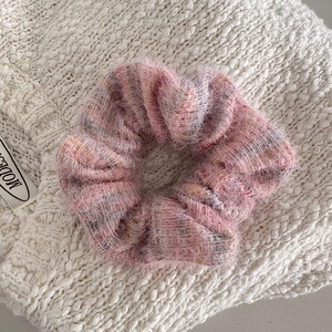 Close-up of pink fuzzy knit scrunchie with soft fluffy texture on a white knit background