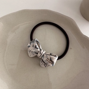 Macro detail of high-elastic bow hair tie with marble acetate and France Handmade text