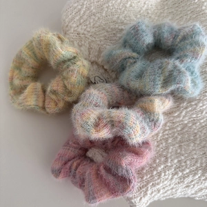 Set of four soft macaron-colored plush hair scrunchies for women in a flat lay view