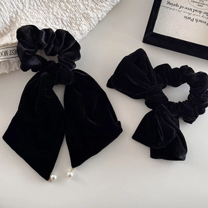 Elegant black velvet hair scrunchies with bow and pearl pendant on a minimalist background