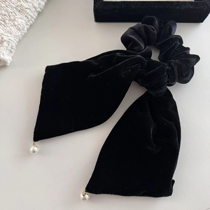 Detail of black velvet scrunchie with long bow streamers and elegant pearl pendants