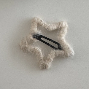 Close-up of star-shaped hair clip with grey hand-knitted wool yarn and metal BB clip