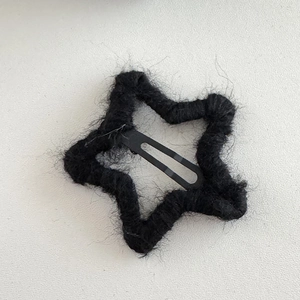 Detailed view of the star-shaped black plush wrapped hairpin with soft yarn texture