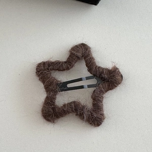 Macro detail of the dark brown fuzzy wool star hair clip with soft plush texture