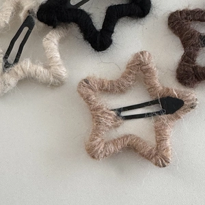 Handmade star-shaped knitted hair clips in assorted colors on a textured gray background
