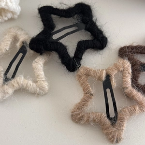 Detail of star-shaped handmade yarn hair clips in neutral colors with plush texture