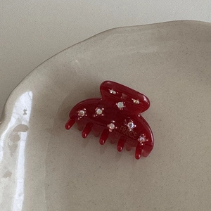 Dettaglio della pinza per capelli in acetato rosso con strass e logo France Hand Made