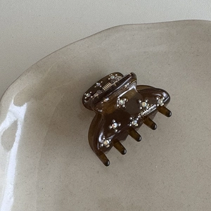 Dettaglio della molletta per capelli in acetato marrone con strass e incisione manuale