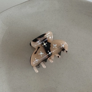 Dettaglio del fermaglio per capelli in acetato ambrato con strass e logo