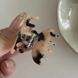 Dettaglio macro di un fermaglio per capelli in acetato tartarugato con molla in metallo oro