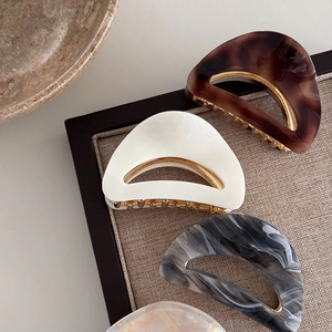 Three acetate hair claws with leopard and marble patterns on golden metal base