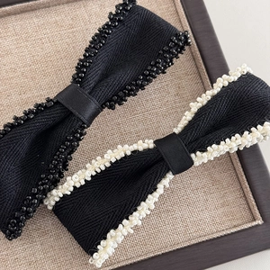 Detailed macro view of beaded edge texture on black bow hair clips with craftsmanship