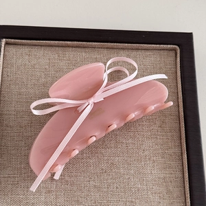 Dettaglio della pinza per capelli rosa con fiocco in raso su base minimalista