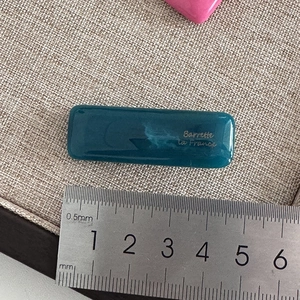 Close-up of a 5cm dark green rectangular barrette showing length with a measuring ruler