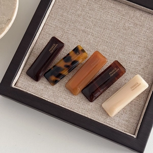 Detailed macro view of five rectangular acetate hair clips in varied tortoiseshell patterns