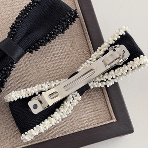 Detail of elegant bow hair clip with beaded edges and metal spring fastener