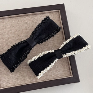 Detail shot of beaded edge bow hair clip with textured fabric and hand-sewn beads
