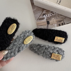Détail de barrettes en laine tricotée avec étiquettes dorées sur un bureau neutre