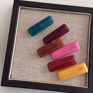 Set of colorful resin rectangular hair barrettes in vibrant glossy finishes with gold labels