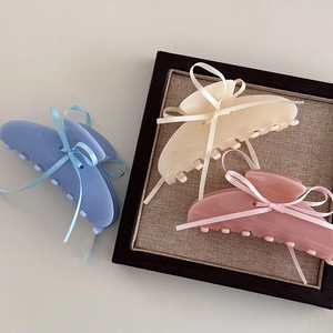 Vista dettagliata di mollette per capelli in acetato con fiocchi in raso blu, beige e rosa