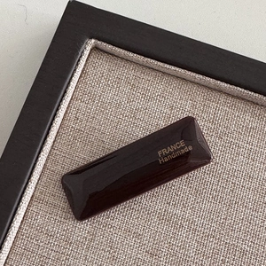 Close-up of minimalist dark brown acetate hair clip with gold France Handmade lettering