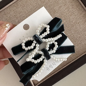 Close-up of handmade velvet bow hair clips with faux pearl detailing on display card
