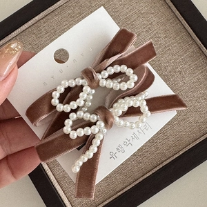 Macro view of velvet hair clips with elegant pearl bow embellishment on display card