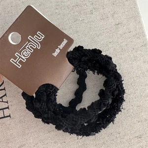 Dettaglio dell'elastico per capelli nero intrecciato con texture su carta di marca