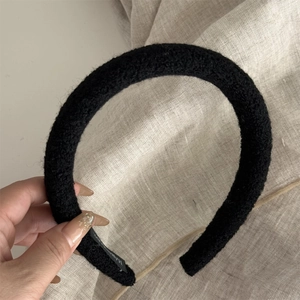 Detail showing plush black thick headband with soft fuzzy texture and woven brand label