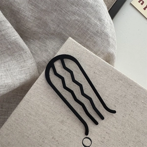 Détail d'une épingle à cheveux en U noir mat pour chignons sur fond de lin neutre