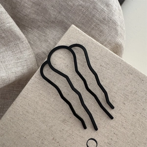 Vue détaillée d'une épingle à cheveux ondulée noir mat sur lin pour chignon élégant