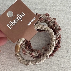 Dettaglio di tre elastici per capelli intrecciati color caffè con perla elegante