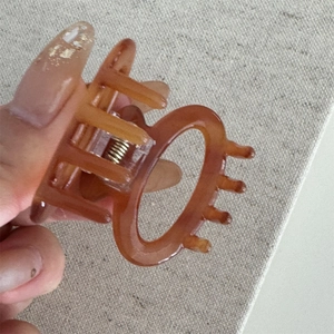 Detailed close-up of amber tortoiseshell acetate hair claw clip with strong metal spring