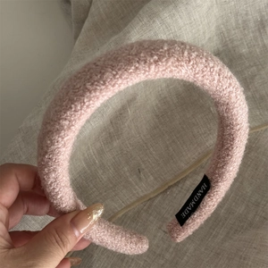 Detail of pink faux shearling headband featuring a woven handmade label on the inner side
