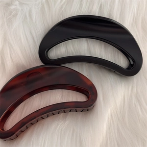 Pinces à cheveux en forme de croissant noir mat et écaille sur fond blanc en peluche