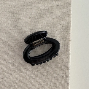 Detail view of a black acetate hair claw with gold France Handmade lettering