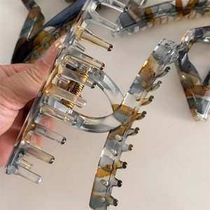 Macro detail of large marble-pattern acetate hair claw clip with strong metal spring