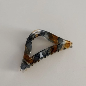 Detail showing the retro marble pattern acetate hair claw and golden metal spring