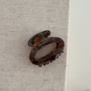 Detail of tortoise shell acetate hair claw clip with France Handmade text on linen