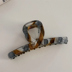 Detail view of tortoiseshell pattern acetate hair claw clip with golden metal spring