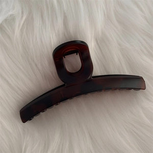 Détail d'une grande pince à cheveux mate ambre avec texture écaille sur fond en peluche