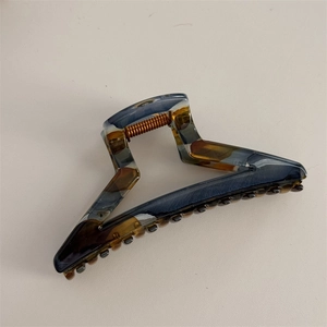Detail view of large acetate claw clip showing dark blue ink texture and copper spring