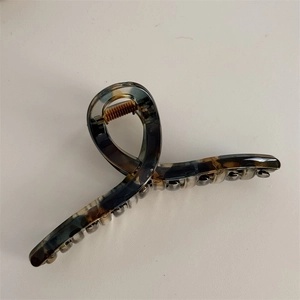 Detail view of acetate claw clip with dark tortoiseshell pattern and metal spring