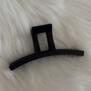 Détail d'une grande pince à cheveux noir mat avec ressort robuste sur fausse fourrure