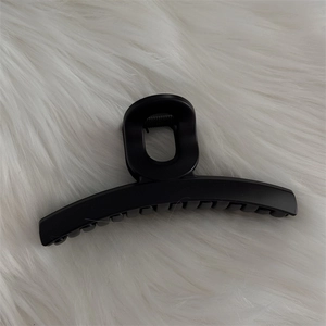 Grande pince à cheveux noire mate avec dents solides sur fond en peluche blanc