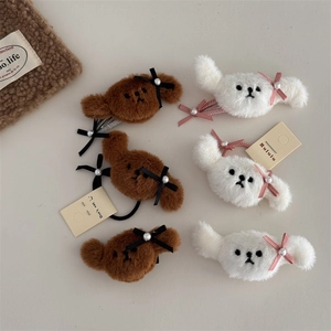 Detalle de pinzas y gomas de pelo de peluche con diseño de perro bichon y lazos