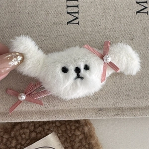 Detalle de pinza de pelo de perrito de felpa blanca con lazo rosa y perlas falsas