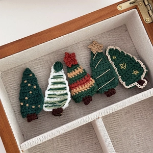 Gros plan de cinq barrettes de Noël en crochet faites à la main dans une boîte en bois