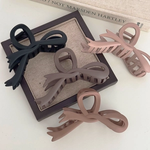 Detailed view of large matte bow hair claws in black, brown, and pink colors